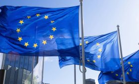 European Union flags waving outside the European Commission building in Brussels representing the EU antitrust approval of the 55 billion EA acquisition