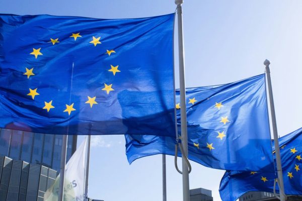 European Union flags waving outside the European Commission building in Brussels representing the EU antitrust approval of the 55 billion EA acquisition