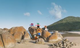 Big Walk characters exploring a sunny beach filled with large rocks