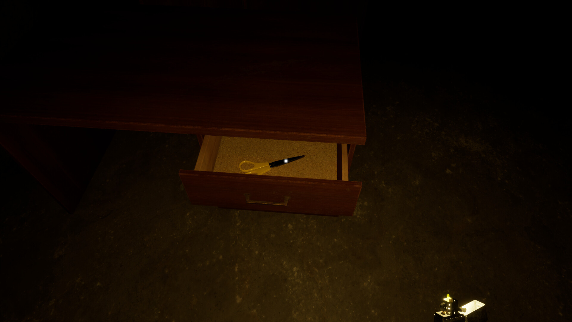 Open drawer containing yellow scissors viewed from above in the dark