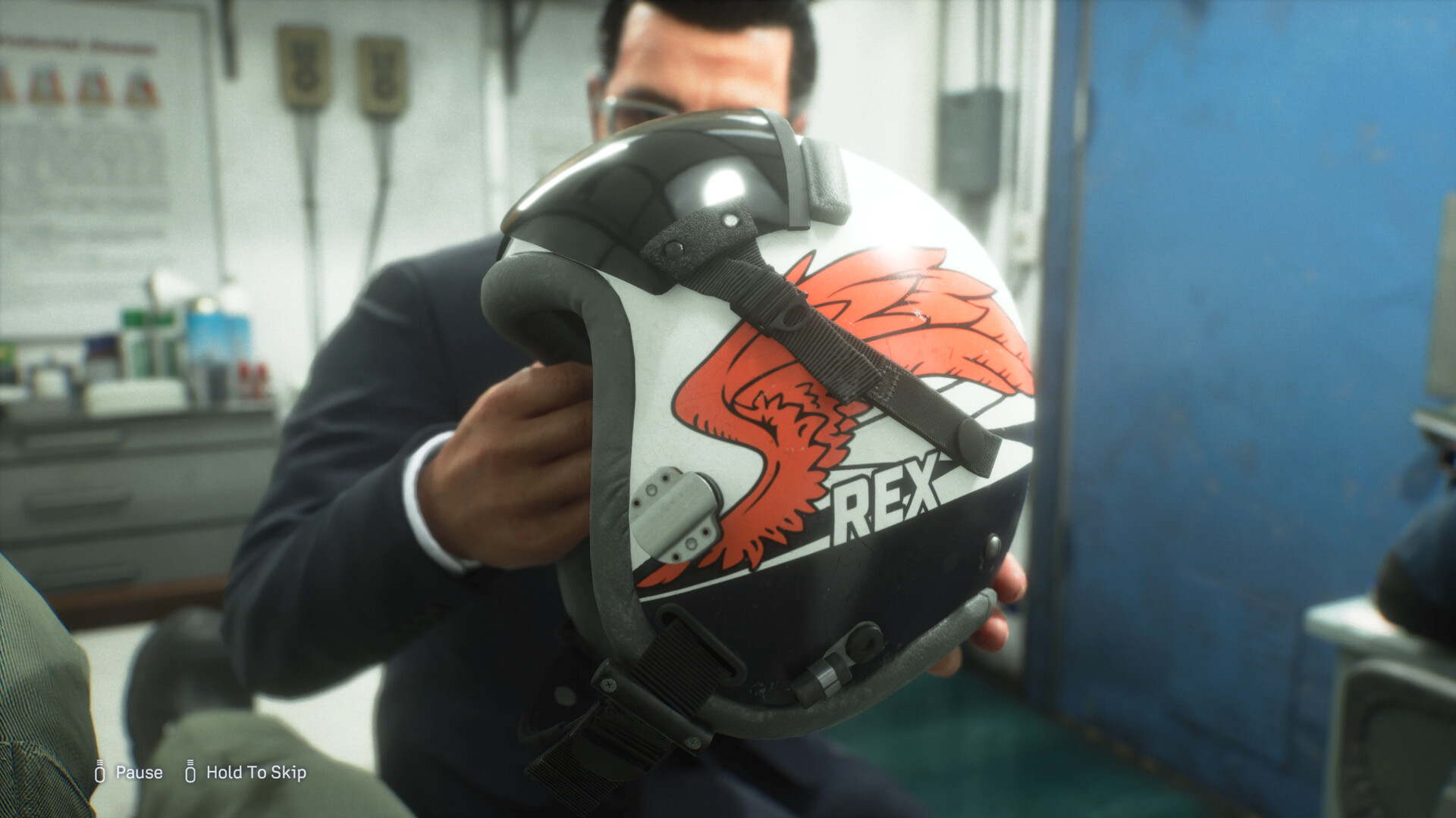 A pilot grips a painted squadron helmet in a pre-mission briefing room